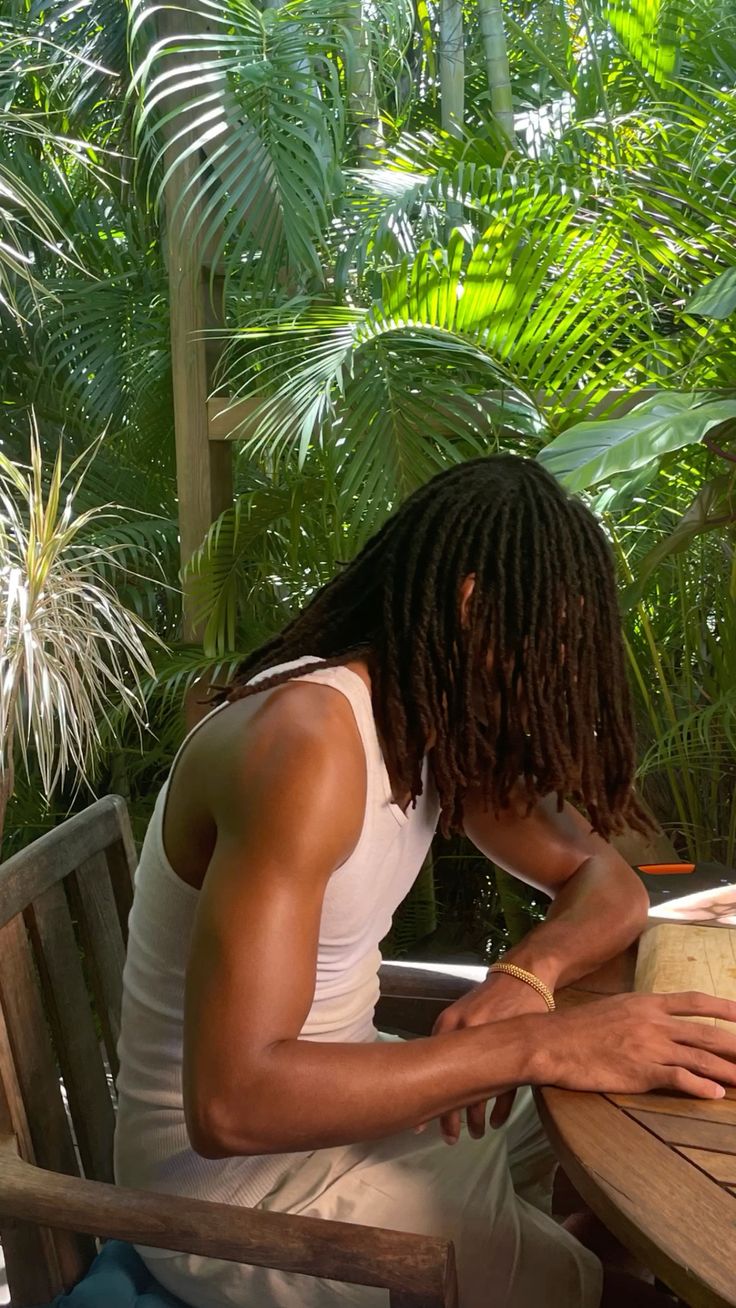 a sitting man with a long locs